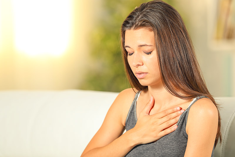woman holding her chest because her heart is beating rapidly