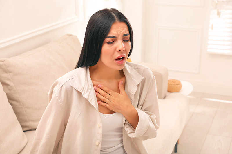 Adult woman holding her chest because she's having difficulty breathing