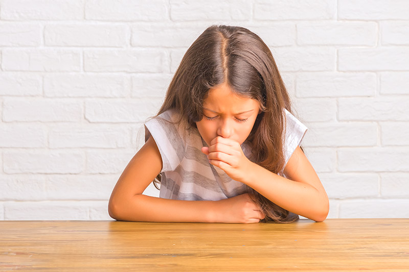 Young girl with bronchitis coughing into her fist