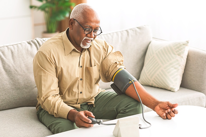 Elderly male sitting on couch and taking blood pressure