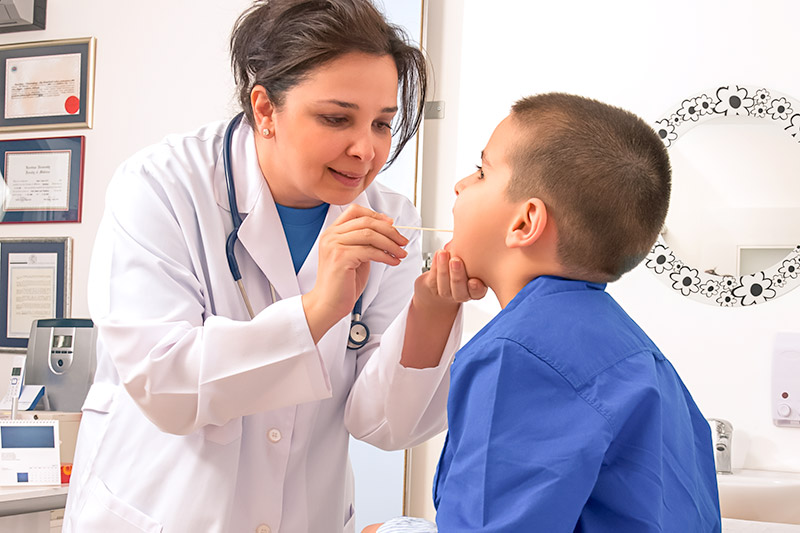 doctor checking little boy's throat