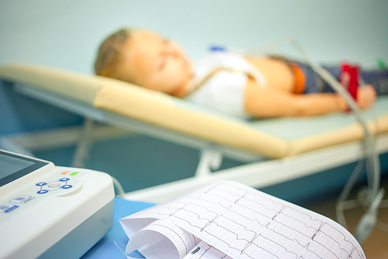 Young girl on hospital bed with electrocardiogram, cardiac cardiograph