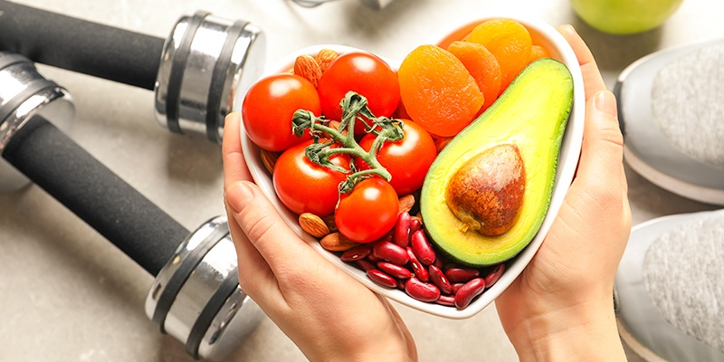 hands holding heart bowl with fruits and vegetables