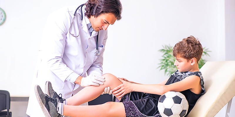 doctor looking at young boys leg with injury