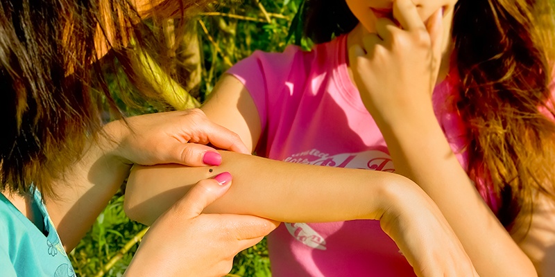young girl with tick stuck on her arm