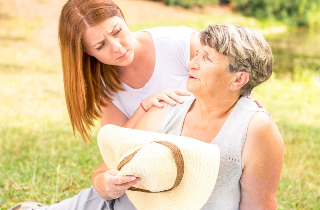 heat exhausted woman sitting on the ground holding hat up to chest