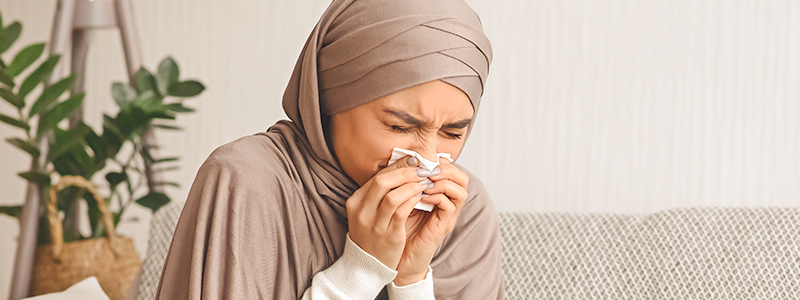 woman blowing runny nose in kleenex