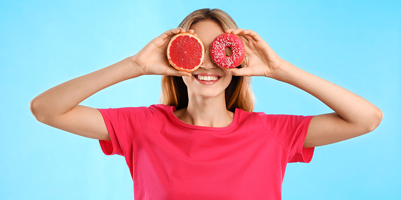 young woman holding donuts over her eyes