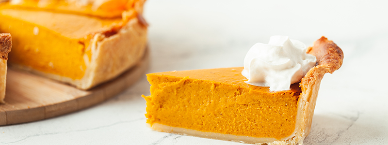 Cut slice of pumpkin pie close up on white background
