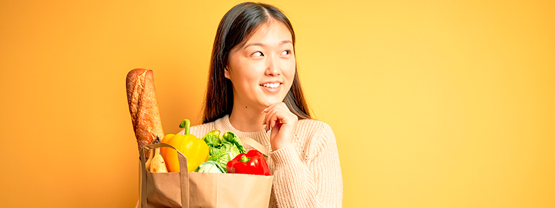 Young asian woman holding paper bag of fresh healthy groceries