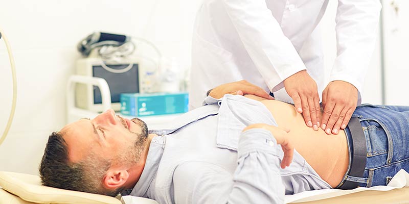 man getting stomach pain checked by doctor
