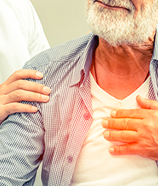 man with beard holding his heart in pain