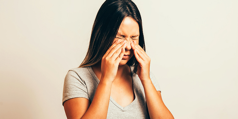 Sinus pain, sinus pressure, sinusitis. Woman holding her nose and head because sinus pain