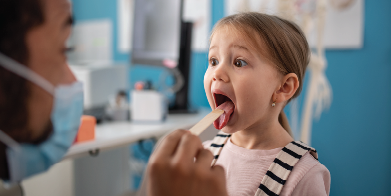 doctor inspecting a child's mouth 