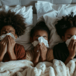 Three sick children resting in bed, each with a tissue in hand, showing signs of the Flu.