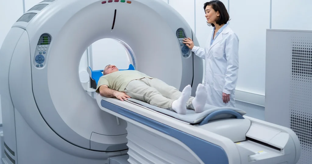 Patient undergoing a CT scan with a technician standing by.