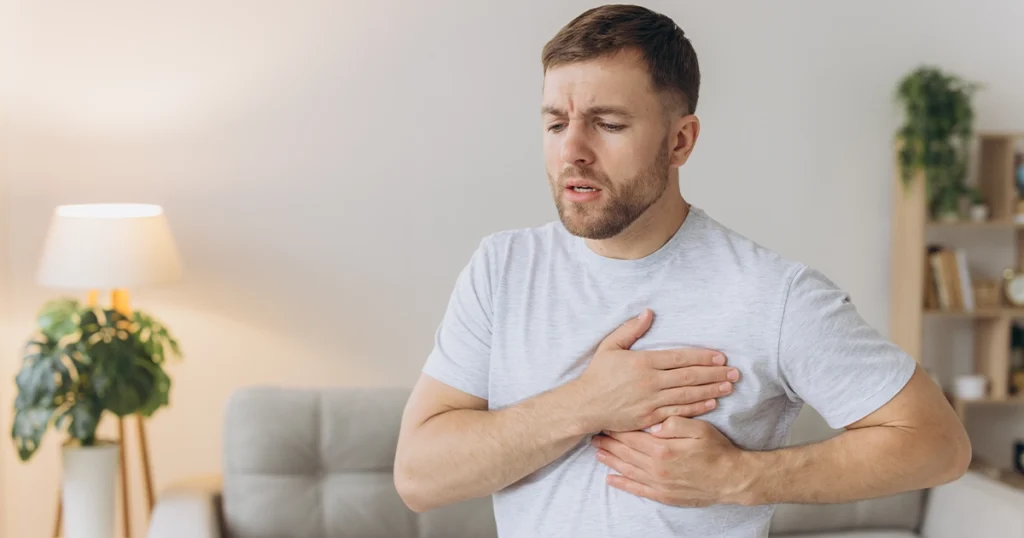 Man experiencing chest pain while standing indoors.