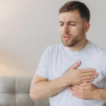 Man experiencing chest pain while standing indoors.