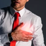 Man experiencing left-side chest pain, holding his chest.