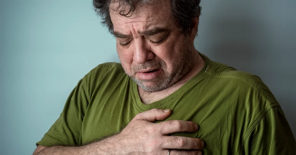 A man experiencing anxiety, holding his chest in pain.
