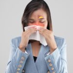 A woman blowing her nose with a tissue, showing symptoms of a sinus infection contagious illness.