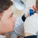 A doctor examines a young boy's ears for fluid in the ear, with medical tools visible in the background.