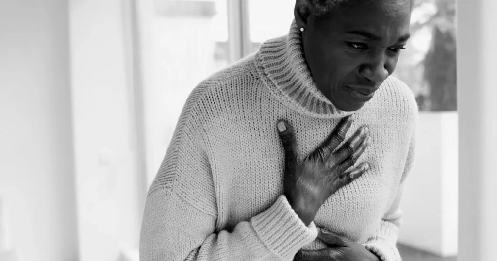 Woman clutching chest, acid reflux causing breathing discomfort.