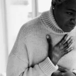 Woman clutching chest, acid reflux causing breathing discomfort.