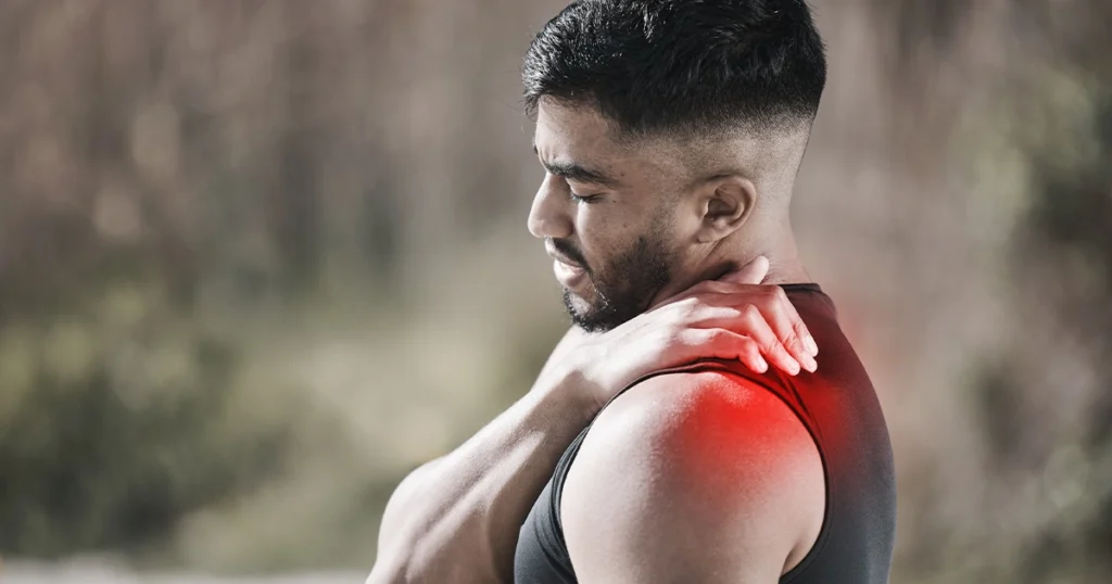Man clutching painful shoulder with red highlighted muscle area.
