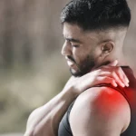 Man clutching painful shoulder with red highlighted muscle area.