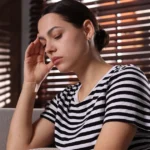 Woman appearing fatigued, possibly due to high cholesterol.