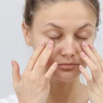 Woman gently applying cream to soothe irritated under-eye skin.