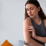 Woman experiencing moving itch and checking irritated skin