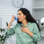 Woman treating wheezing episode with quick-relief inhaler.