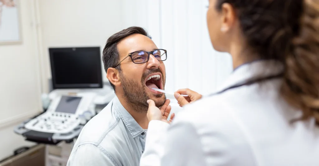 Doctor examining a patient’s throat with a tongue depressor.