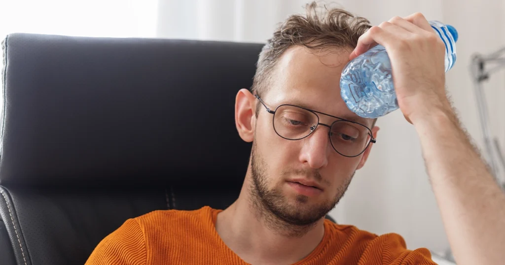 Man experiencing dehydration causes headaches at work.
