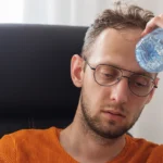 Man experiencing dehydration causes headaches at work.