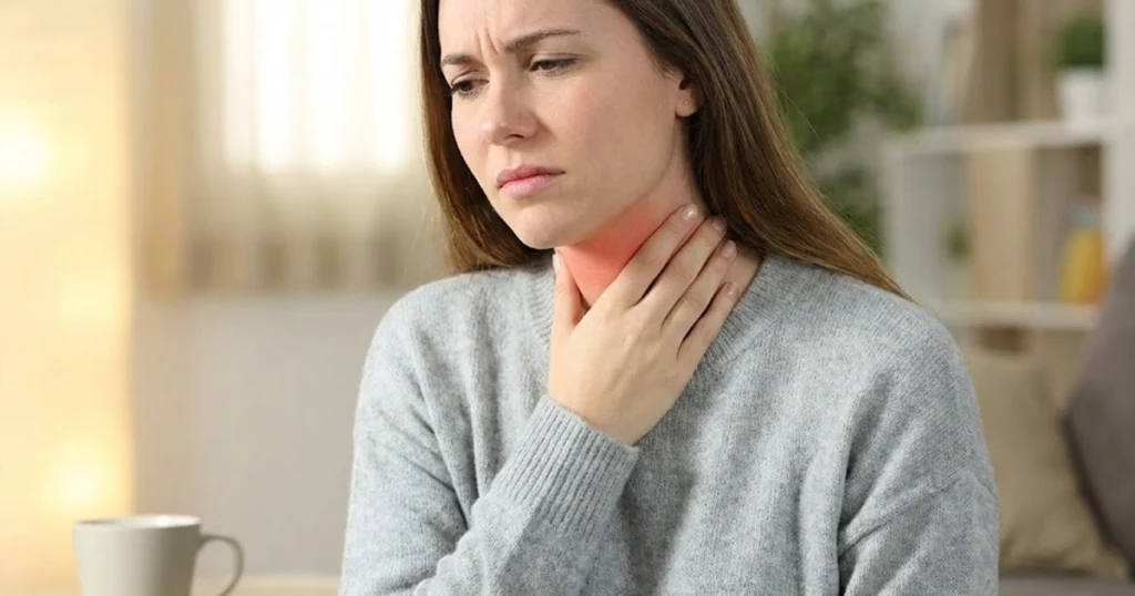 Woman experiencing sore throat pain.