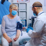 A doctor checks the blood pressure of a patient in a medical clinic, demonstrating ways to manage hypertension.