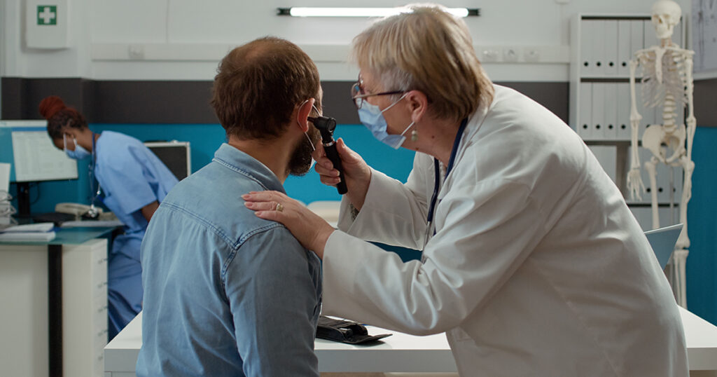 A doctor uses an otoscope to examine a patient’s ear, illustrating how ear infections can lead to jaw pain.