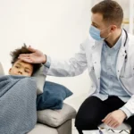 A doctor wearing a mask checking a sick child's forehead for fever.