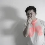 Man coughing with a red highlighted graphic on his chest showing lung inflammation.