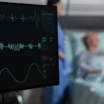 Hospital patient monitor displaying continuous heart rate and vital readings.
